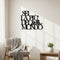 Black wooden wall art with Italian phrase 'Sei la più bella del mondo' in minimalist living room with armchair and plant