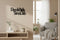 Modern living room with wooden wall decor phrase Piccola Stella Senza Cielo, gray armchair, plants, and neutral tones