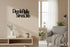 Modern living room with wooden wall decor phrase Piccola Stella Senza Cielo, gray armchair, plants, and neutral tones