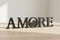 Black wooden decorative letters spelling AMORE placed on light wood surface in bright room