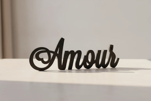 Black wooden decorative script word 'Amour' on a light surface, modern home decor