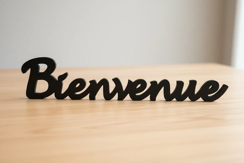 Black wooden Bienvenue sign on light wood surface for home decoration