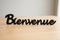 Black wooden Bienvenue sign on light wood surface for home decoration