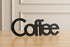 Black wooden decorative word 'Coffee' on wooden table with beige paneled wall background