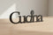 Black wooden kitchen decoration with the word 'Cucina' and a spoon detail on a light wooden surface