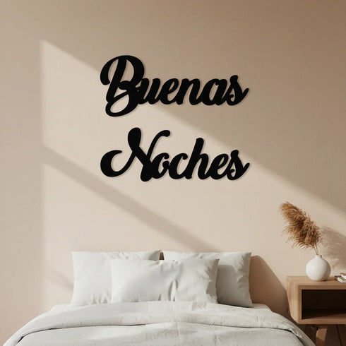 Bedroom wall decoration with black wooden 'Buenas Noches' sign above white pillows and bed