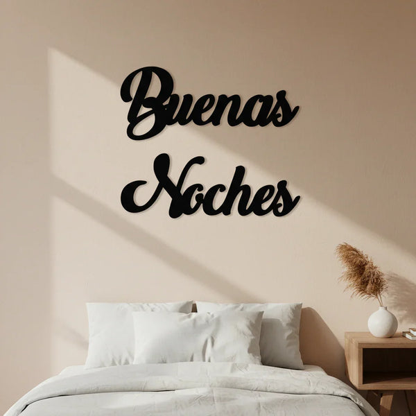 Bedroom wall decoration with black wooden 'Buenas Noches' sign above white pillows and bed