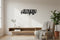 Minimalist living room with wooden bench, armchair with gray knit throw, potted plant, and black wall art saying Buongiorno Principessa