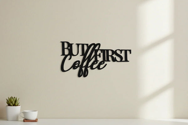 Black wooden wall decor sign with 'But First Coffee' text in modern home setting with small plant and white cup