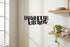 Black farmhouse kitchen wooden wall sign with shelves holding plates and a trailing potted plant