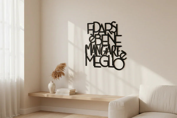 Minimalist living room with black wooden wall art reading 'FIDARSI È BENE MANGIARE MEGLIO', beige couch and dried plant decor