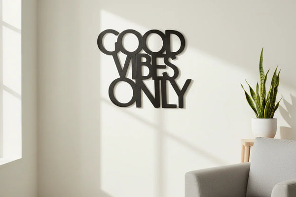 Black wooden wall decoration with Good Vibes Only text in bright living room with potted plant and gray sofa