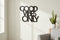 Black wooden wall decoration with Good Vibes Only text in bright living room with potted plant and gray sofa