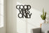 Black wooden wall decoration with Good Vibes Only text in bright living room with potted plant and gray sofa