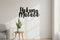 Modern living room with grey sofa, wooden side table, potted plant, and black wooden Hakuna Matata wall decor