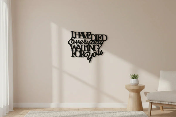 black wooden wall decoration with text 'I have died everyday waiting for you' in minimalist beige living room