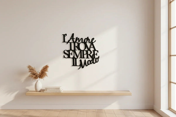 Modern minimalistic interior with wooden floating shelf, pampas grass vase, books, and black Italian wall art saying "L'amore trova sempre il modo"