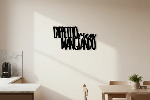 Modern kitchen dining area with wooden table, chairs, green plant, espresso machine, and black Italian wall decor saying 'L'appetito vien mangiando'