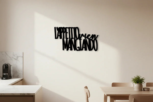 Modern kitchen dining area with wooden table, chairs, green plant, espresso machine, and black Italian wall decor saying 'L'appetito vien mangiando'