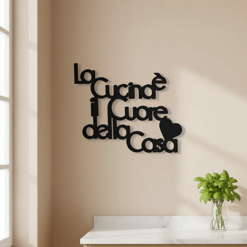 Black wooden wall decor reading 'La Cucina è il Cuore della Casa' with a heart shape on beige kitchen wall above white marble countertop with green basil plant
