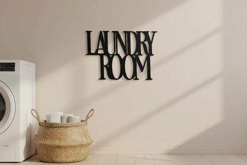 Laundry room decor with black wooden wall sign, white washer, and woven basket with towels