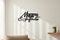 Black wooden wall decor with Italian phrase 'Mamma amore infinito' in modern living room with beige sofa and small plant