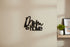 Black wooden wall decor sign reading 'Mom is Home' on beige wall in cozy home setting