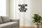 Minimalist living room with grey sofa, potted plant, and black wooden wall decor listing New York Paris London Roma