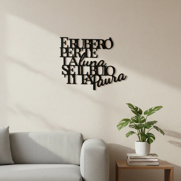 Modern living room with light gray sofa and wooden side table holding potted green plant and books, wall decor with Italian phrase in black lettering
