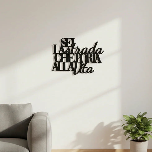 Black wooden wall decor with Italian inspirational phrase above sofa and potted plant in a bright living room