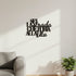 Black wooden wall decor with Italian inspirational phrase above sofa and potted plant in a bright living room