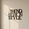 Modern black metal wall decor with overlapping words Trend Fashion Style on beige wall