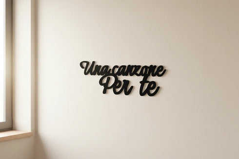 Black wooden wall decoration with Italian phrase Una canzone per te in a minimalist room near window