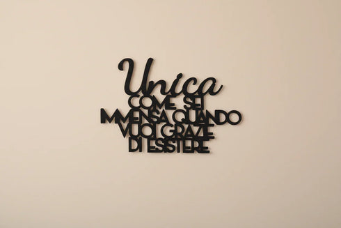 Black wooden wall decoration with Italian motivational quote on a beige wall