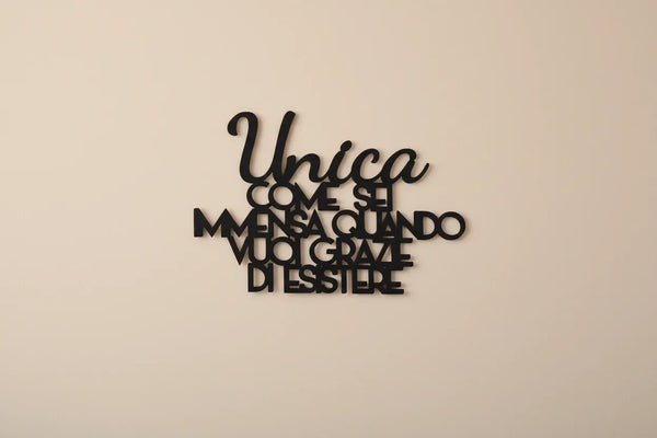 Black wooden wall decoration with Italian motivational quote on a beige wall