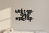 Black wooden wall decor with phrase 'wake up and make up' above a white marble surface and a small candle