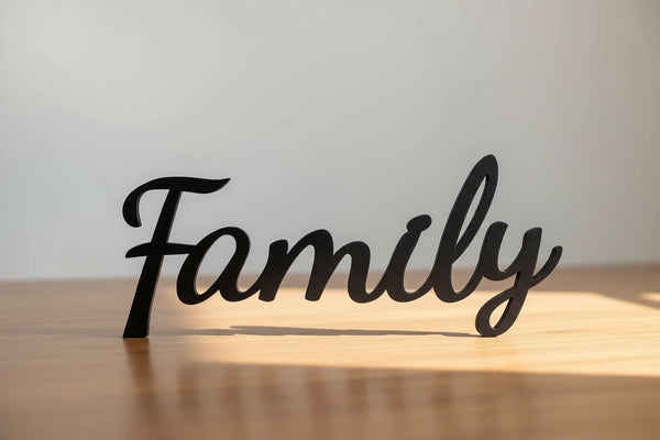 Black wooden decorative word 'Family' on wooden table with light and shadow, home decor