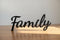 Black wooden decorative word 'Family' on wooden table with light and shadow, home decor