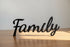 Black wooden decorative word 'Family' on wooden table with light and shadow, home decor