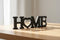 Black wooden decorative word HOME with heart shape as O on wooden surface, home decoration