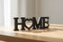 Black wooden decorative word HOME with heart shape as O on wooden surface, home decoration