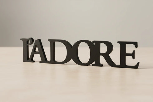 Black wooden L'ADORE decorative home decor lettering on light wooden surface