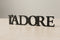 Black wooden L'ADORE decorative home decor lettering on light wooden surface