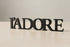 Black wooden L'ADORE decorative home decor lettering on light wooden surface
