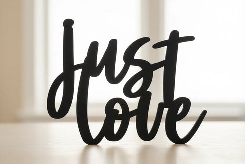 Black wooden 'just love' decorative sign on table with soft natural light background