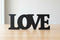 Black wooden decorative letters spelling LOVE on wooden surface with white background for home decor