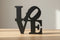 Black wooden decorative letters forming the word LOVE on a light wooden surface for home decor