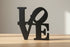 Black wooden decorative letters forming the word LOVE on a light wooden surface for home decor