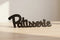 Black wooden decorative word sign 'Patisserie' on light wooden surface for home decor