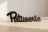 Black wooden decorative word sign 'Patisserie' on light wooden surface for home decor